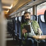 man sitting in train using tablet
